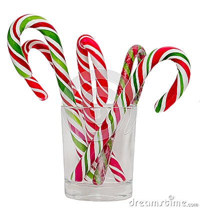 Colored candy sticks and Christmas lollipops in a transparent glass, isolated, white background. Stock Photo