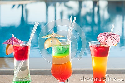 Colored cocktails on a background of water. Colorful cocktails near the pool. Beach party. Summer drinks. Stock Photo