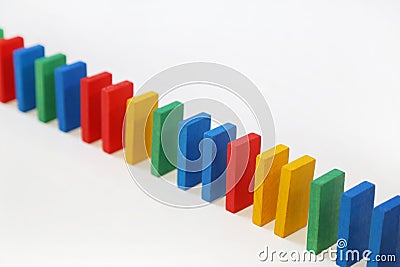 Colored dominoes stand in a row on a white background. A chain reaction dominoes Stock Photo