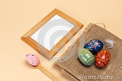 Colored Easter eggs on a sackcloth bag and a photo frame. Stock Photo