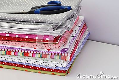 Colored fabric folded stack with scissors on the gray background Stock Photo