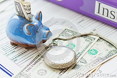 Colored folders, piggy bank, clean insurance form and a pocket watch Stock Photo