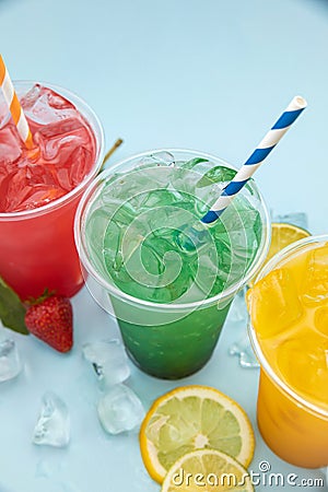 Colored lemonades in plastic cups with ice, fruits and berries Stock Photo