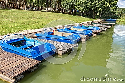 Colored old vintage plastic catamarans and boats near a wooden pier on the shore of a large lake Stock Photo