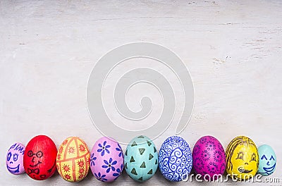 Colored ornamental eggs for Easter with painted faces border ,place for text wooden rustic background top view close up Stock Photo