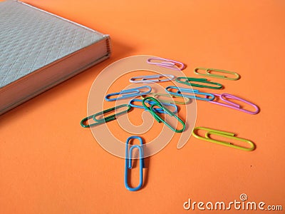 Colored paper clips on orange background Stock Photo