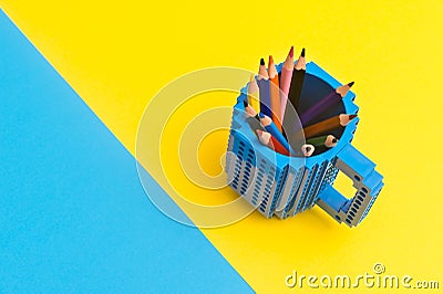Colored pencils in a bucket on blue and yellow background. Back to scool concept Stock Photo