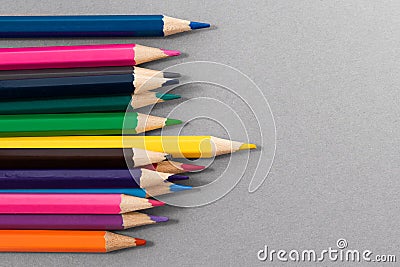 Colored pencils on gray paper with space to write to the right. Crowd concept. Focus on yellow pencil in foreground Stock Photo