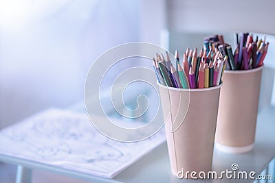 Stack of colored pencils in a glass on wooden background,top view. A cozy place to draw for kids. Stock Photo