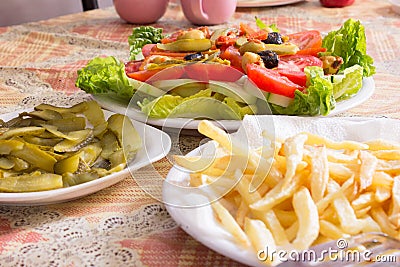 Colored salad and frensh fries with Pickled Cucumber on white plates Stock Photo