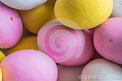 Colored sweet little eggs. Multi-colored Easter eggs on a plate. Sweet Easter eggs shot close up. Festive chocolate eggs in pink, Stock Photo