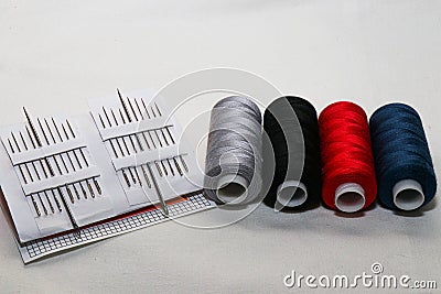 Colored threads and needles. Everything you need for sewing. Several spools of thread. Sharp needles.Red, black, gray and blue thr Stock Photo