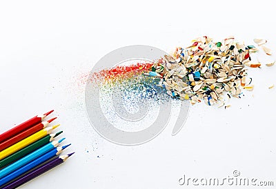 Colored watercolor pencils of rainbow colors and shavings from them after sharpening on a white background. Stock Photo