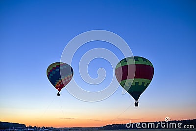 Colorful Air Balloons Levitating Over the Field Outdoors Against Clear Blue Skies At Twilight Stock Photo