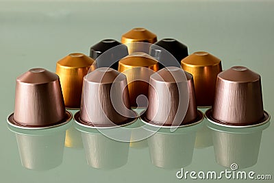 Colorful aluminum coffee capsules on gray glass with reflection Stock Photo
