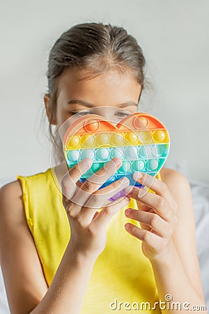 Colorful antistress sensory toy fidget push pop it in kid's hands. Stock Photo