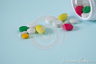 Colorful, assorted pharmaceutical medicine pills poured out of the bottle. many pills and tablets isolated on blue Stock Photo