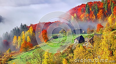 Colorful autumn landscape in the mountain village. Foggy morning Stock Photo