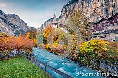 Colorful autumn view of great waterfall in Lauterbrunnen village with azure river. Editorial Stock Photo