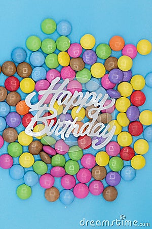 Colorful background for birthday party invitation with smarties sweets and the words happy birthday on blue background Stock Photo