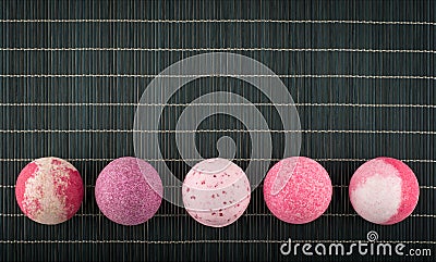 Colorful bath bombs arranged in a row on a bamboo placemat Stock Photo