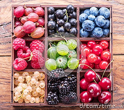 Colorful berries in wooden box on the table. Top view Stock Photo