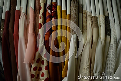 colorful blouses hanging on white hangers, arranged by color Stock Photo