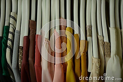 colorful blouses hanging on white hangers, arranged by color Stock Photo