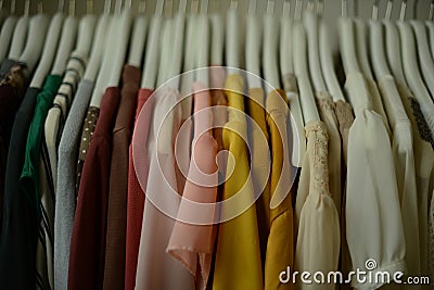 colorful blouses hanging on white hangers, arranged by color Stock Photo