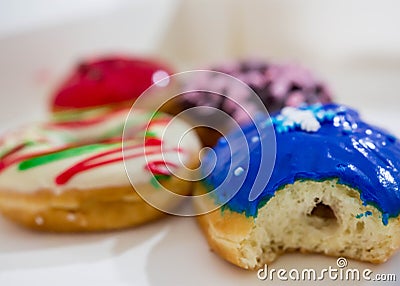 Colorful blue with bite, red, brown and stripes donuts with white background Stock Photo