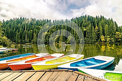 Colorful boats on the lake with the reflection of green trees in Lacu Rosu, Romania Stock Photo