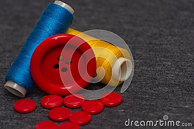 Colorful bright threads for sewing and red buttons. Gray blurred background. Sewing industry. Atelier design elements Stock Photo