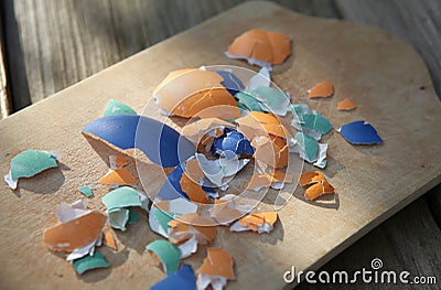 Colorful broken Easter eggshells on a wooden cutting board Stock Photo