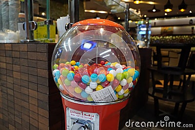 Colorful bubble gum in Coin operated gumball machine. Carousel Gumball Machine Bank kept outside a shop. - Dubai UAE January 2020 Editorial Stock Photo