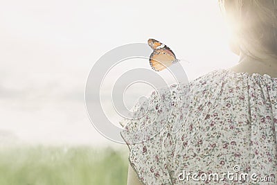 A colorful butterfly leans delicately on the shoulders of a girl Stock Photo