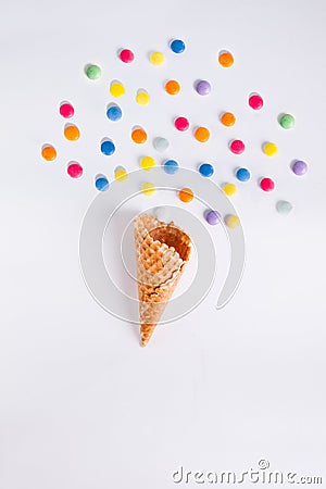 Colorful candies bang from ice cream cone on the white background. Place for lettering. Top view, flat lay. Stock Photo