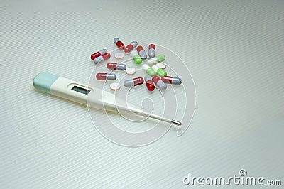 Colorful capsule medicine pills and a digital thermometer on white background. Stock Photo