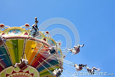 Colorful chain swing carousel in motion at amusement park on blue sky background. Editorial Stock Photo