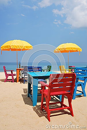 Colorful chair and table with yellow umbrella on the beach Stock Photo