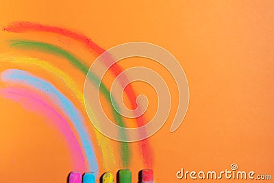 Colorful chalks drawing a rainbow on a orange background Stock Photo