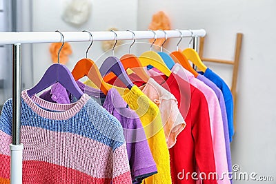 Colorful children`s clothes hanging on wardrobe rack indoors Stock Photo