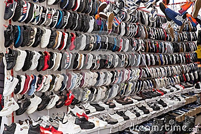 Colorful Chinese sneakers are hung in rows in the market. Sale of fashionable sneakers. Russia, Abakan 23.09.2019. Editorial Stock Photo