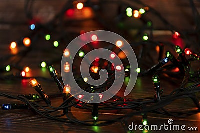 Colorful christmas garland lights on brown wooden background. Christmas Light with Copyspace for New Year Frame or Christmas Layou Stock Photo