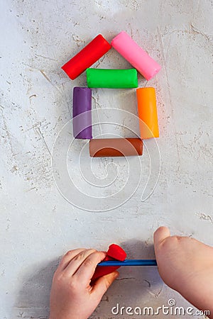 Colorful clay plasticine, modelling clay placed like house with child`s hands, vertical, education, child psychology, Stock Photo