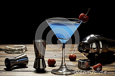 Colorful cocktail blue martini recipe with red cherry and bartender accessories on the wooden table in black background Stock Photo