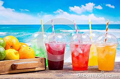 Colorful cold drinks in plastic cups on the beach Stock Photo