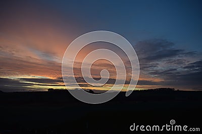 colorful dawning day sky above a dark hill Stock Photo