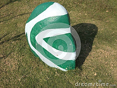 Colorful decorated stone just for show or decorum on green field. Stock Photo