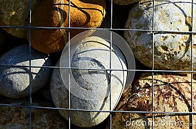 Colorful decorative smooth river stone closeup in galvanized wire mesh cage Stock Photo