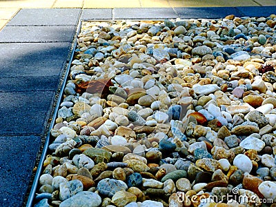 Decorative smooth colorful river stone in closeup view. square shape tree planter. Stock Photo